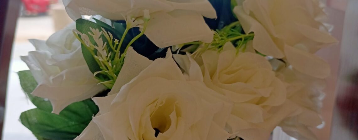 Bunch of white artificial flowers with green leaves.
