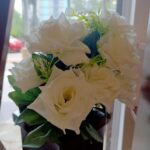 Bunch of white artificial flowers with green leaves.