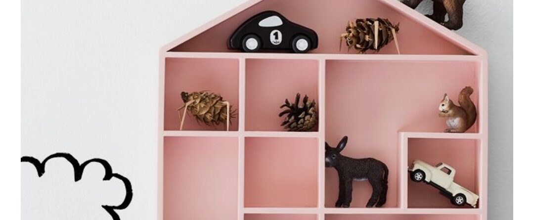 Pink house-shaped wall shelf with toys.