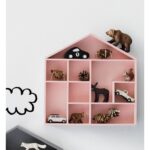 Pink house-shaped wall shelf with toys.